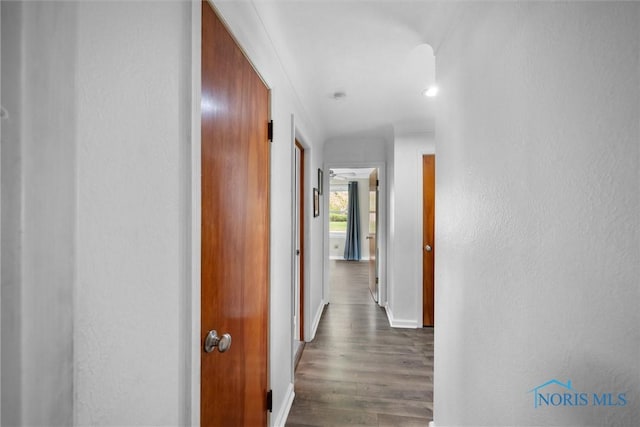 corridor featuring dark wood finished floors and baseboards