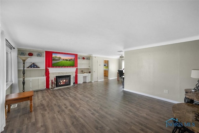 unfurnished living room with visible vents, a stone fireplace, wood finished floors, and baseboards