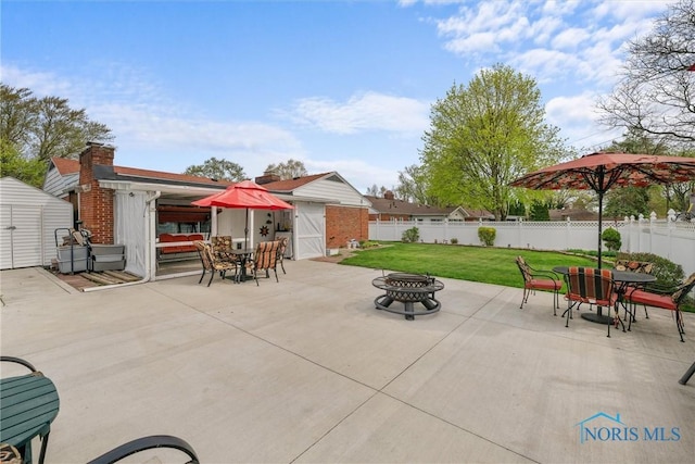 view of patio / terrace with outdoor dining area, an outdoor fire pit, an outdoor structure, a shed, and fence