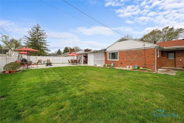 back of house with a lawn, a fenced backyard, and brick siding