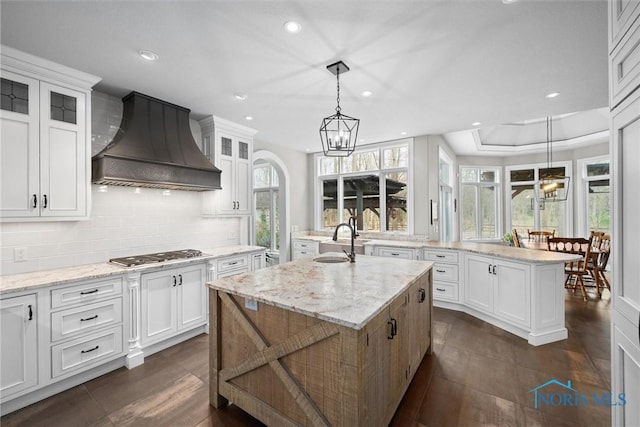 10915 Reed Rd, Monclova, OH 43542 - kitchen with a kitchen island with sink, glass insert cabinets, stainless steel gas stovetop, backsplash, and premium range hood