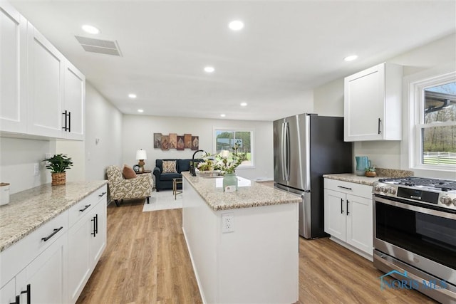 kitchen featuring visible vents, stainless steel appliances, a healthy amount of sunlight, and a center island