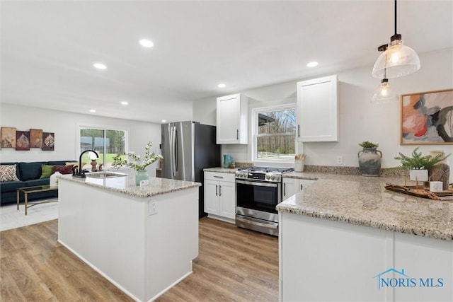 kitchen featuring appliances with stainless steel finishes, light stone countertops, white cabinets, and a sink