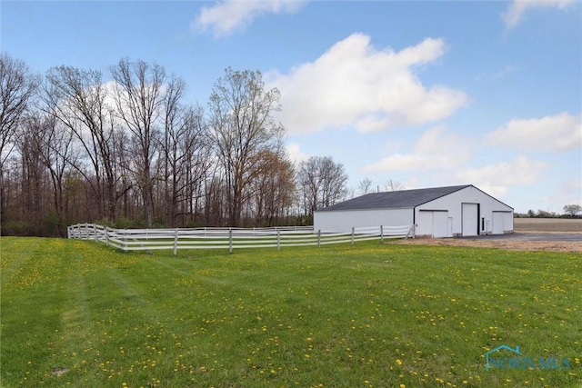 view of yard with an outbuilding, a detached garage, a pole building, and fence