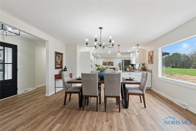 dining room featuring visible vents, an inviting chandelier, baseboards, and light wood-type flooring