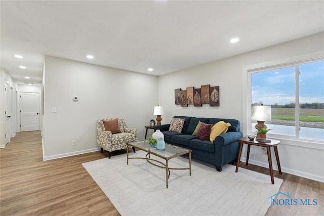 living room with light wood finished floors, recessed lighting, and baseboards