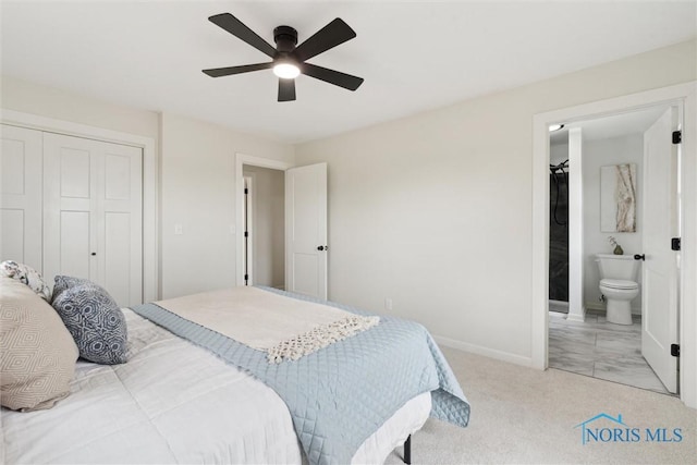 bedroom with a closet, ensuite bath, a ceiling fan, baseboards, and light colored carpet