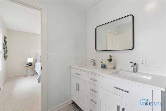 ensuite bathroom featuring double vanity, a sink, connected bathroom, and baseboards