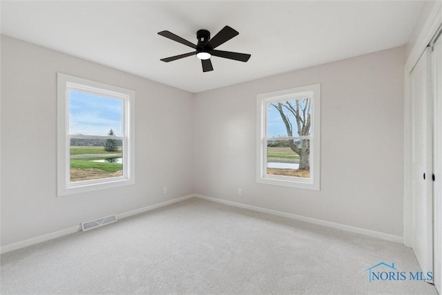 unfurnished bedroom featuring a closet, visible vents, light colored carpet, and multiple windows
