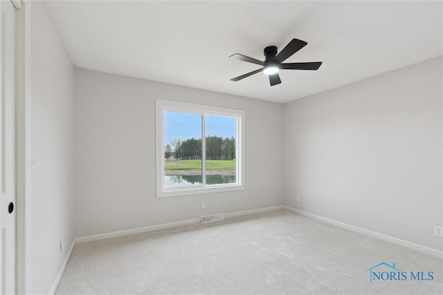 carpeted empty room featuring a ceiling fan, visible vents, and baseboards