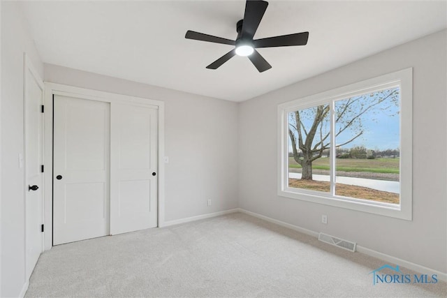unfurnished bedroom featuring light colored carpet, visible vents, a closet, and baseboards