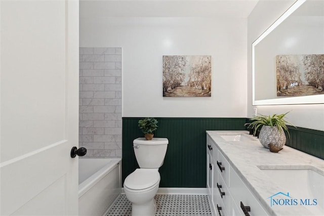 bathroom with toilet, a wainscoted wall, a sink, and double vanity