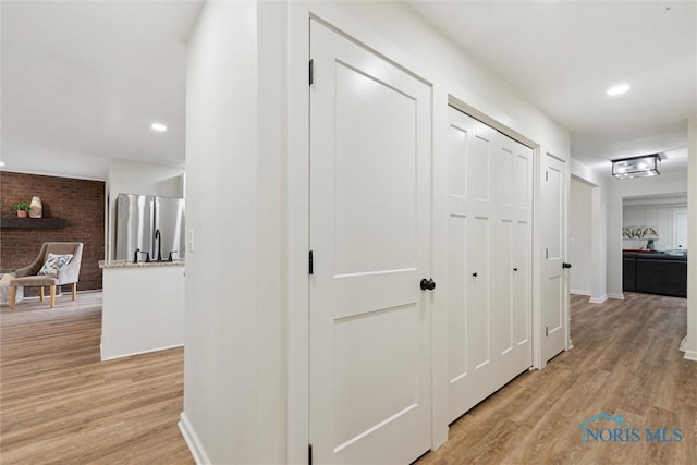 hallway featuring light wood finished floors, recessed lighting, and baseboards