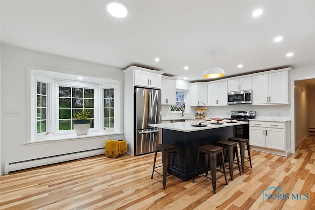 19788 Otsego Pike, Bowling Green, OH 43402 - kitchen with a healthy amount of sunlight, a breakfast bar, appliances with stainless steel finishes, baseboard heating, and light wood-type flooring