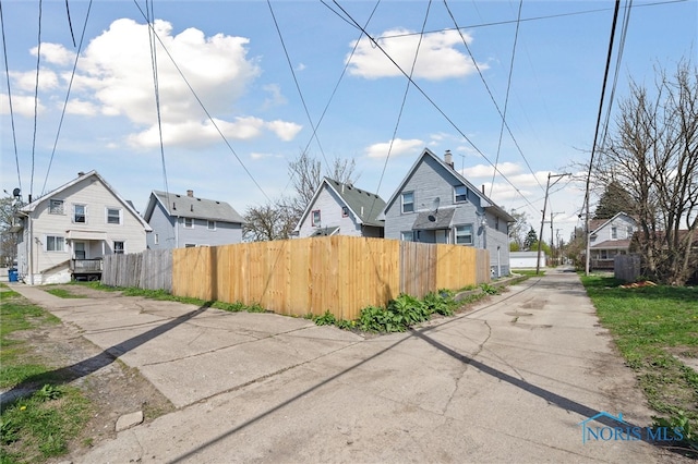 exterior space featuring fence, a residential view, and driveway