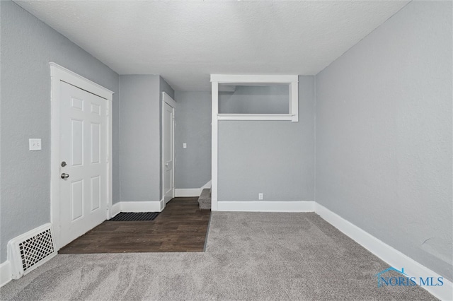 carpeted spare room featuring baseboards, visible vents, and a textured ceiling