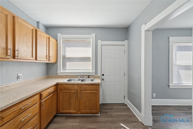 kitchen featuring light countertops, a sink, and dark wood finished floors