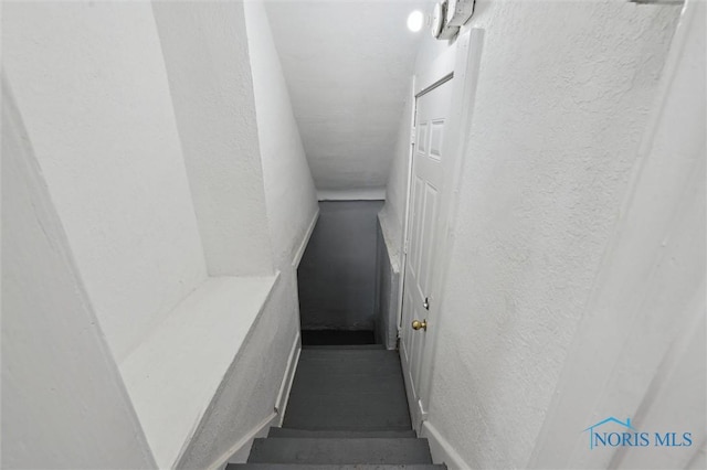 staircase with baseboards and a textured wall
