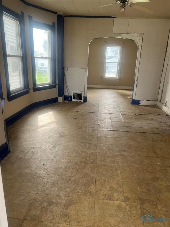 empty room featuring baseboards, visible vents, and arched walkways