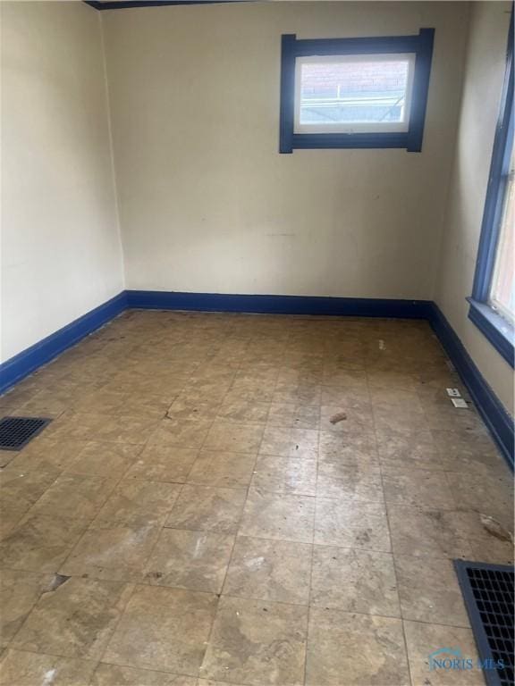spare room with baseboards, visible vents, and a wealth of natural light