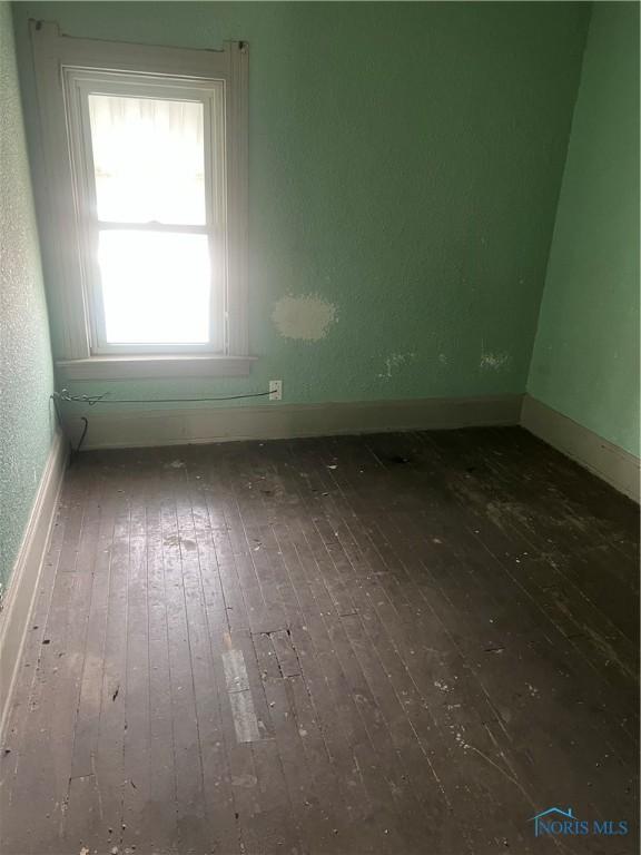 unfurnished room featuring wood-type flooring and baseboards
