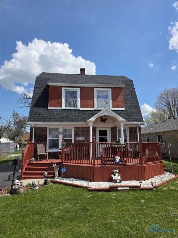 back of house with a yard, a shingled roof, and brick siding