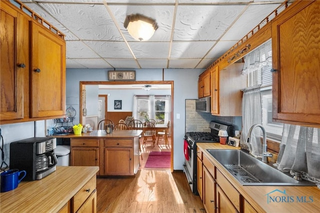 4532 290th St, Toledo, OH 43611 - kitchen featuring stainless steel appliances, a sink, light wood finished floors, ceiling fan, and brown cabinetry