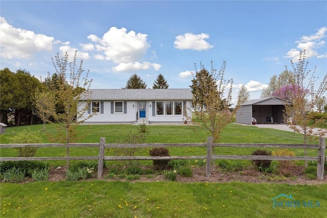 ranch-style home featuring fence, concrete driveway, a front lawn, and an outbuilding
