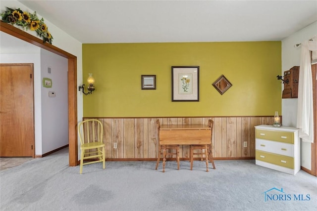 sitting room with baseboards, wainscoting, wooden walls, and carpet flooring
