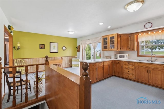kitchen featuring brown cabinetry, a sink, a healthy amount of sunlight, and white microwave