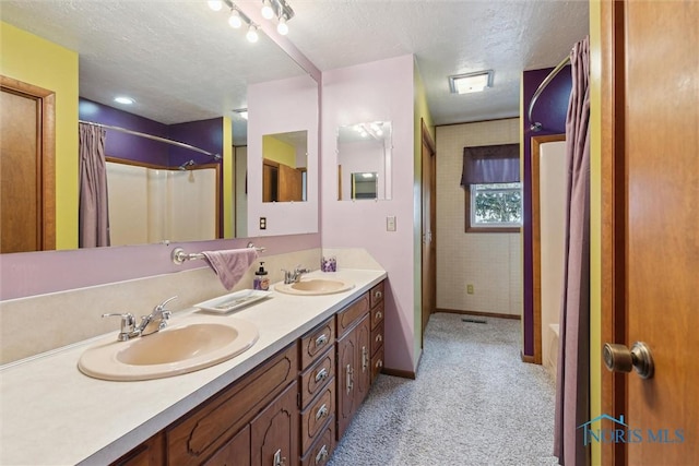 bathroom featuring double vanity, a textured ceiling, baseboards, and a sink