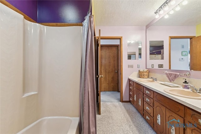 bathroom featuring shower / bath combination with curtain, a textured ceiling, a sink, and double vanity