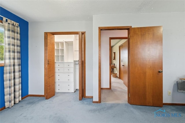 unfurnished bedroom with baseboards, a textured ceiling, and carpet flooring