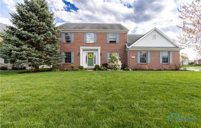 colonial house with a front lawn and brick siding