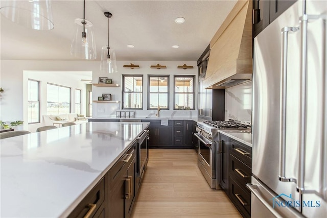 kitchen with recessed lighting, custom exhaust hood, stainless steel appliances, light countertops, and a sink