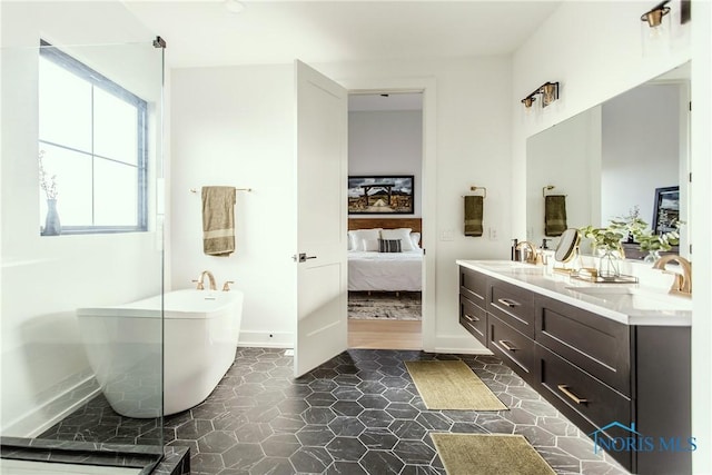 ensuite bathroom featuring double vanity, a freestanding bath, ensuite bath, and a sink