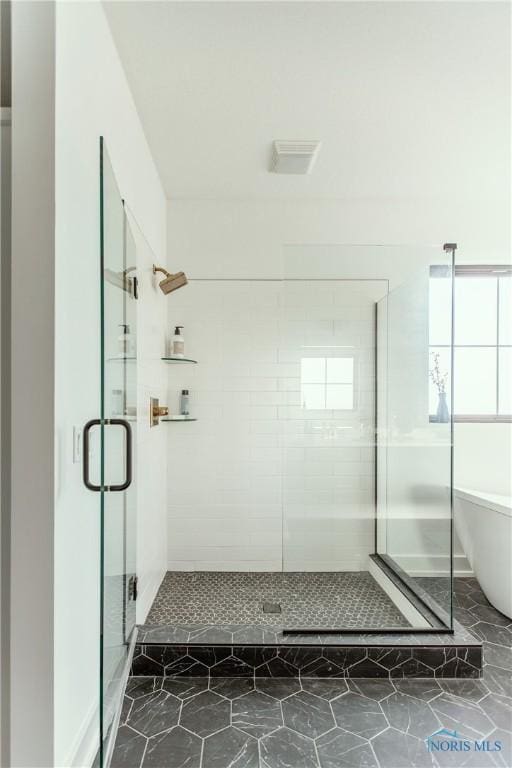 bathroom featuring a soaking tub, visible vents, a stall shower, and a wealth of natural light