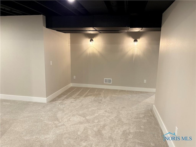finished below grade area featuring light colored carpet, visible vents, and baseboards