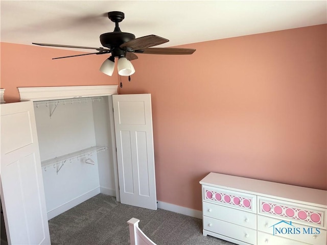 unfurnished bedroom with baseboards, dark colored carpet, and a ceiling fan
