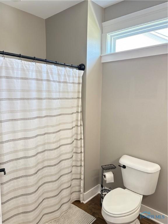 bathroom featuring wood finished floors, toilet, a shower with curtain, and baseboards