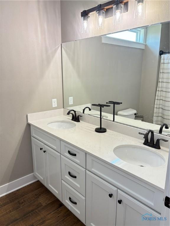 full bathroom with wood finished floors, double vanity, and a sink