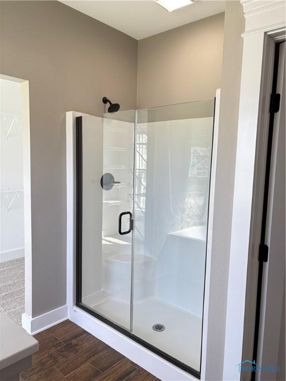 full bath featuring a shower stall, wood finished floors, and baseboards