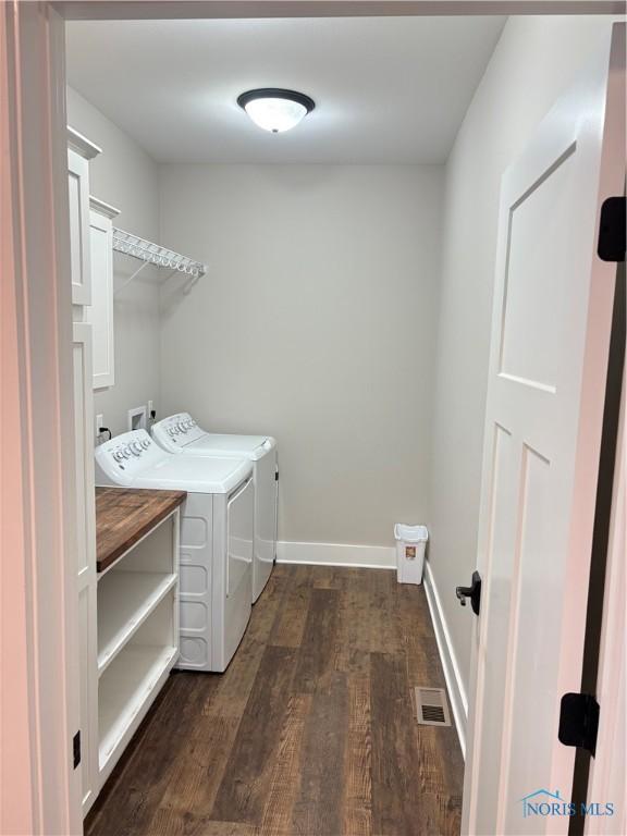 laundry area featuring dark wood finished floors, baseboards, separate washer and dryer, and laundry area