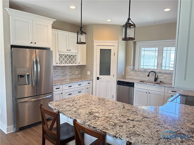 kitchen featuring stainless steel appliances, light stone countertops, dark wood finished floors, and a sink