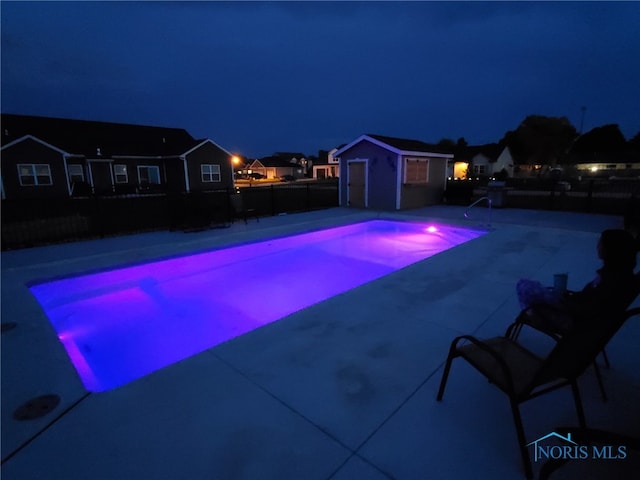 pool at twilight featuring an outdoor structure, a fenced backyard, a fenced in pool, and a patio area