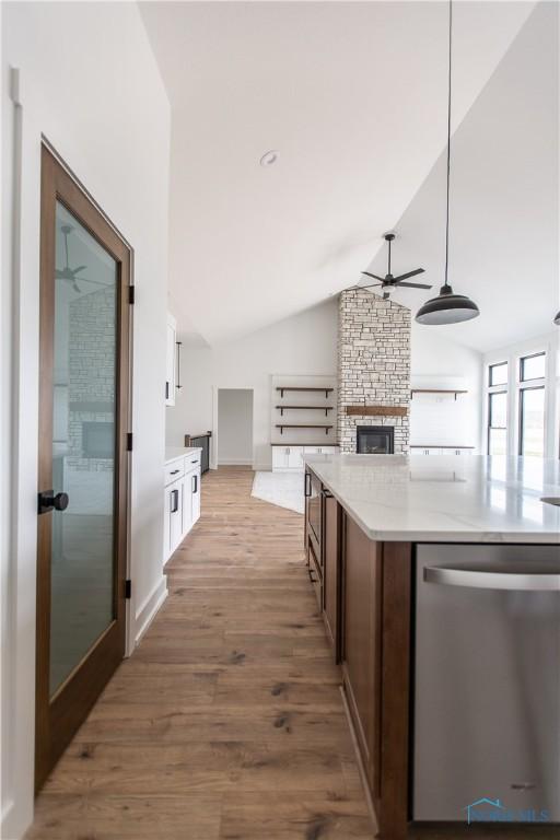 kitchen with light wood-type flooring, a ceiling fan, vaulted ceiling, light countertops, and dishwasher
