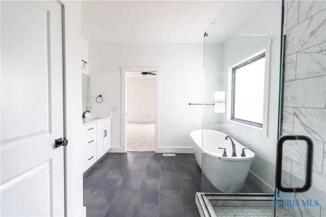 full bath featuring baseboards, tile patterned floors, ceiling fan, vanity, and a soaking tub