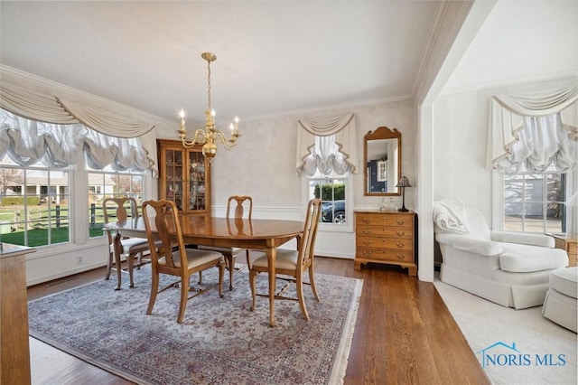 dining room with crown molding, a notable chandelier, a wealth of natural light, and wood finished floors