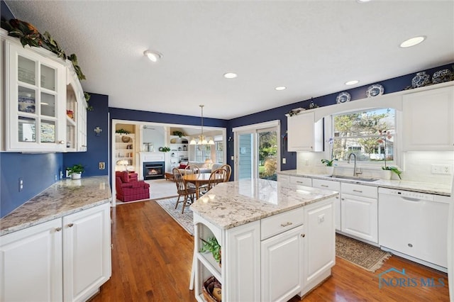 kitchen featuring wood finished floors, dishwasher, white cabinets, and a sink