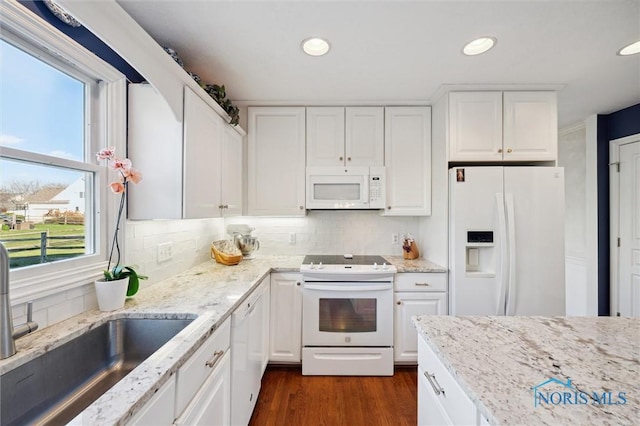 kitchen featuring white appliances, white cabinets, and a sink